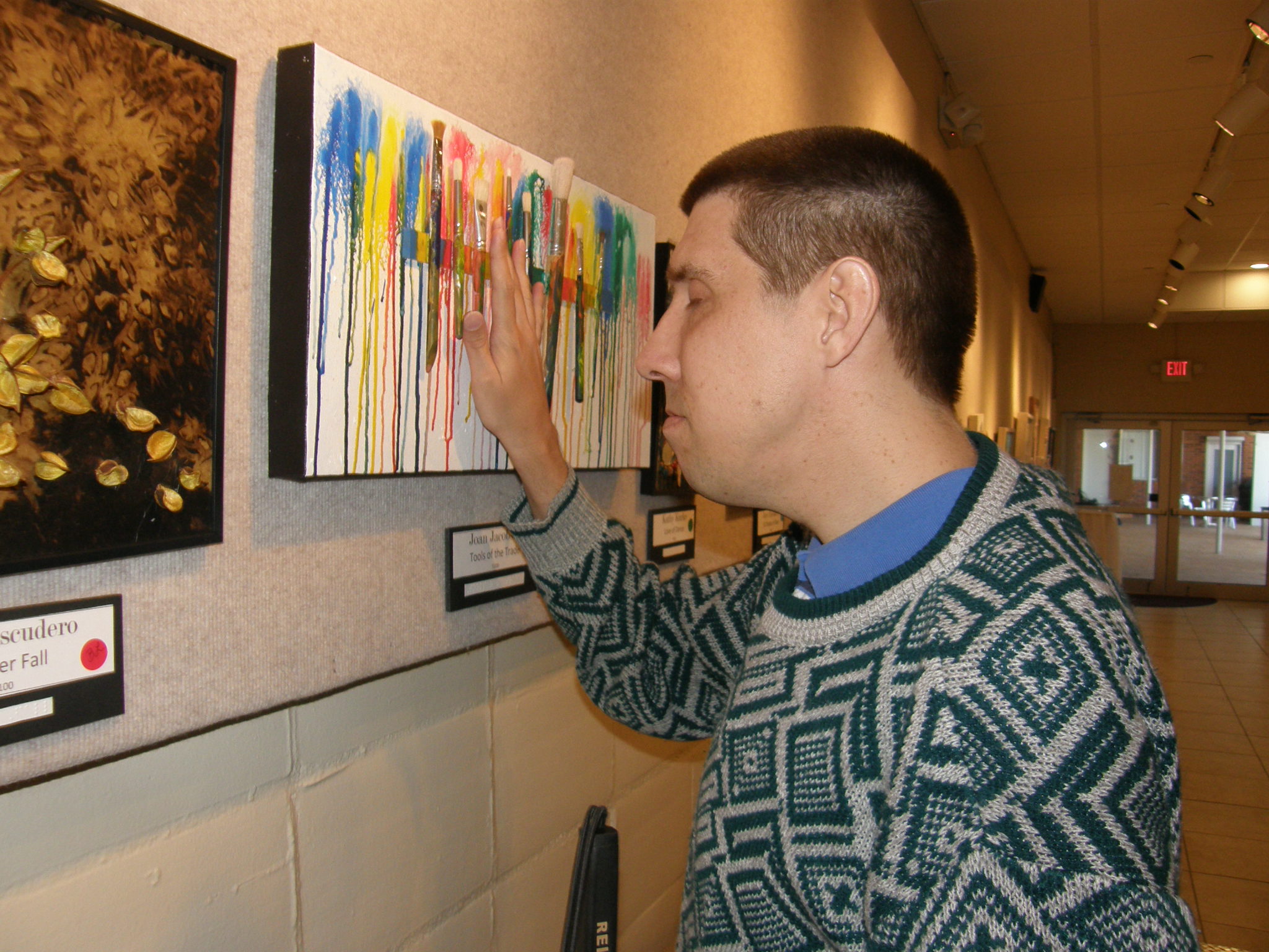 Scott Larson touches the tactile artwork hanging on the wall at the "A Touch of Art" exhibit
